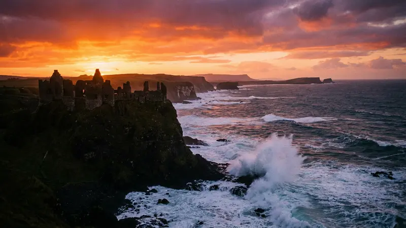 Dunluce Castle ruins dramatically silhouetted against a sunset sky on the Causeway Coast, Northern Ireland