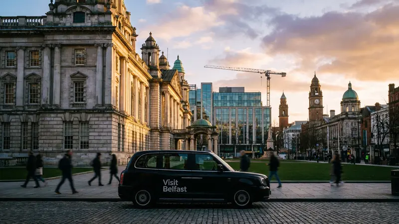 Belfast city skyline at golden hour with historical architecture and a modern car.