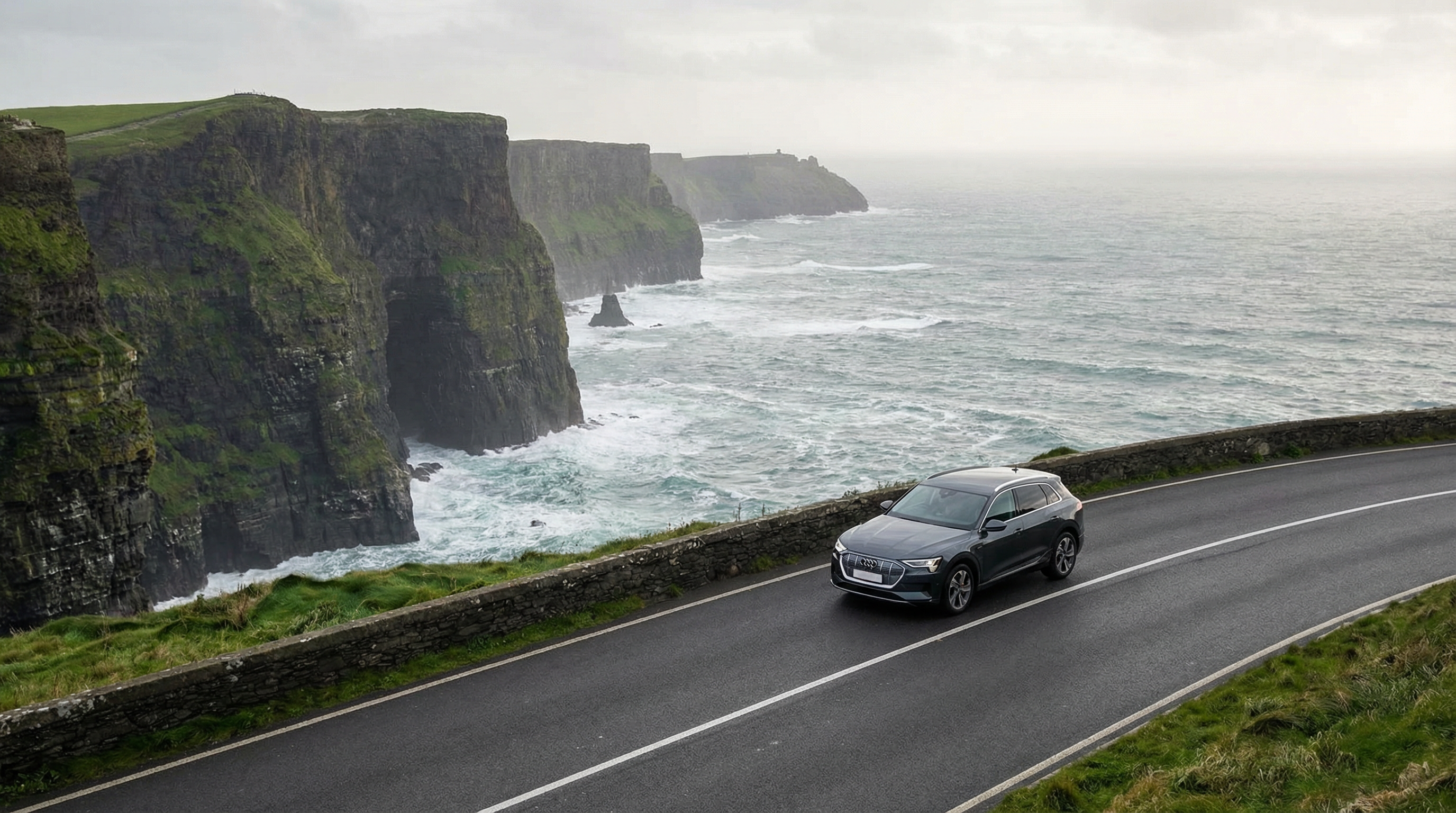 Modern rental car driving on a scenic coastal road in Ireland.
