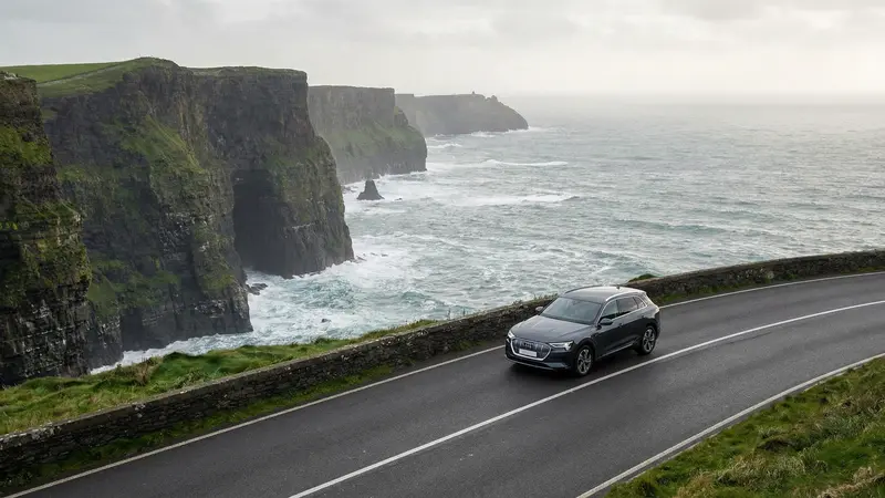 Modern rental car driving on a scenic coastal road in Ireland.