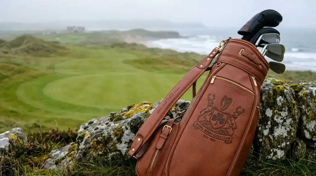 A premium leather golf bag resting against a historic stone wall on an exclusive Irish links course.
