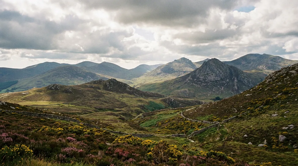 Panoramic view of the rolling, majestic Mourne Mountains landscape under a dramatic sky.
