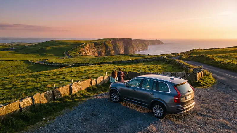 Modern rental car overlooking the dramatic Cliffs of Moher on a self-drive vacation in Ireland at sunset