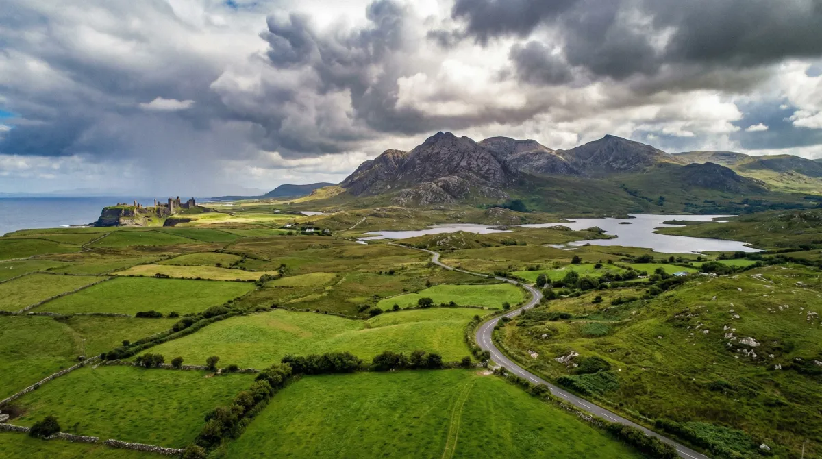 Panoramic view of diverse Irish landscapes with a road and distant castle