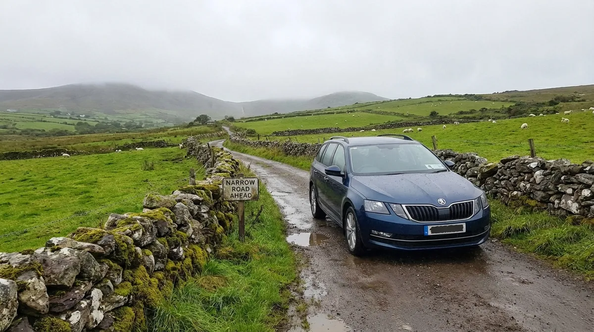 Modern car on a narrow rural Irish road with stone walls, implying insurance needs