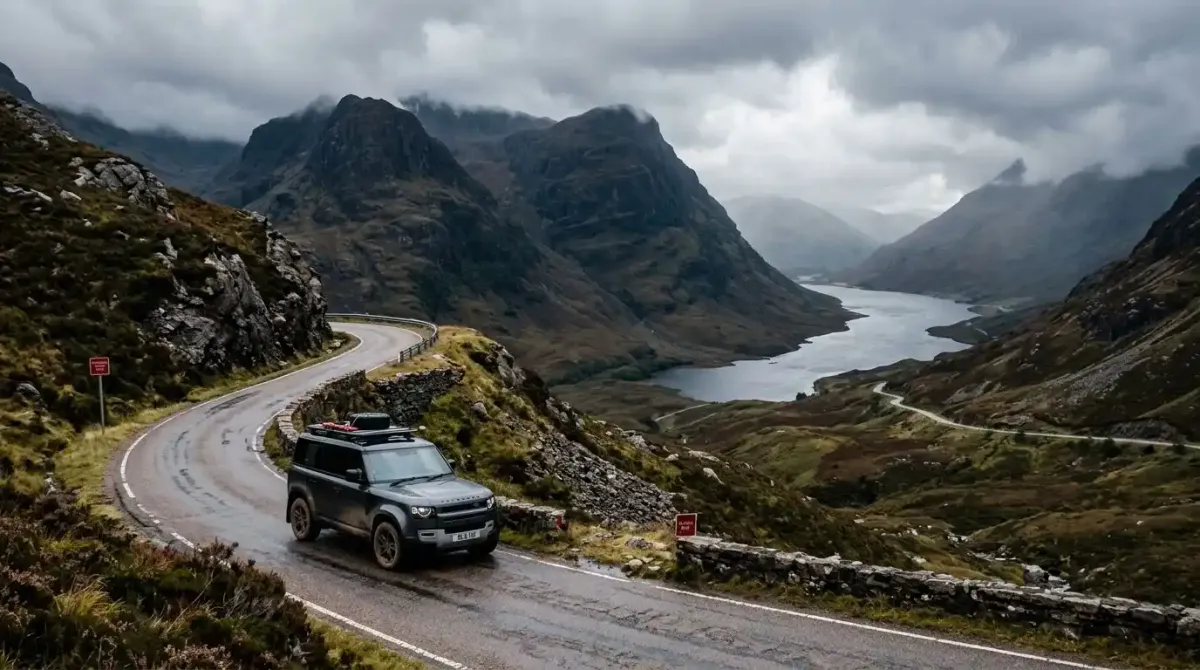 A luxury SUV navigating a mountain pass in the Highlands on a combined Ireland and Scotland vacation package.