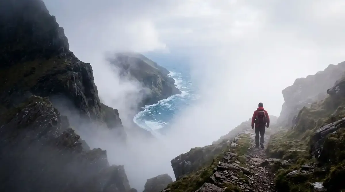 Shifting sea mist and dramatic weather conditions on a high coastal mountain ridge trail in Ireland.