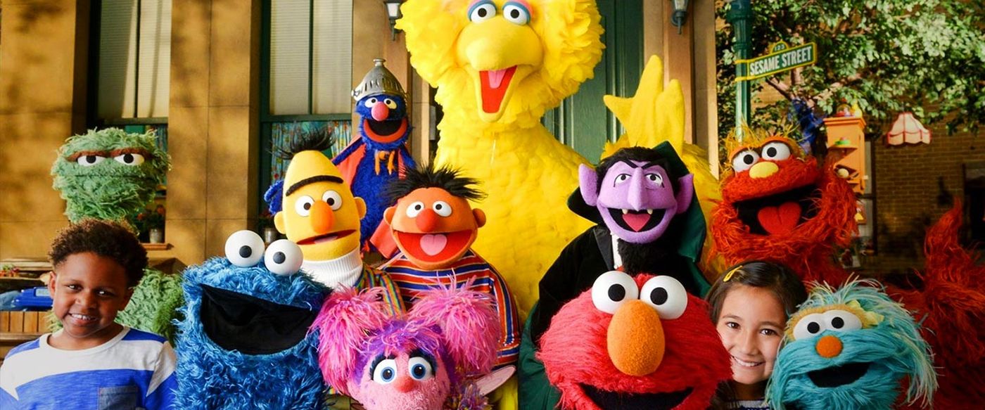 Sesame Street muppet characters including Elmo, Big Bird and Cookie Monster pose with two children