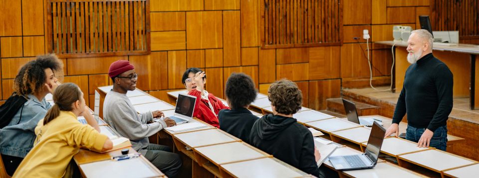 Students in a wood-paneled lecture hall with a professor at the front