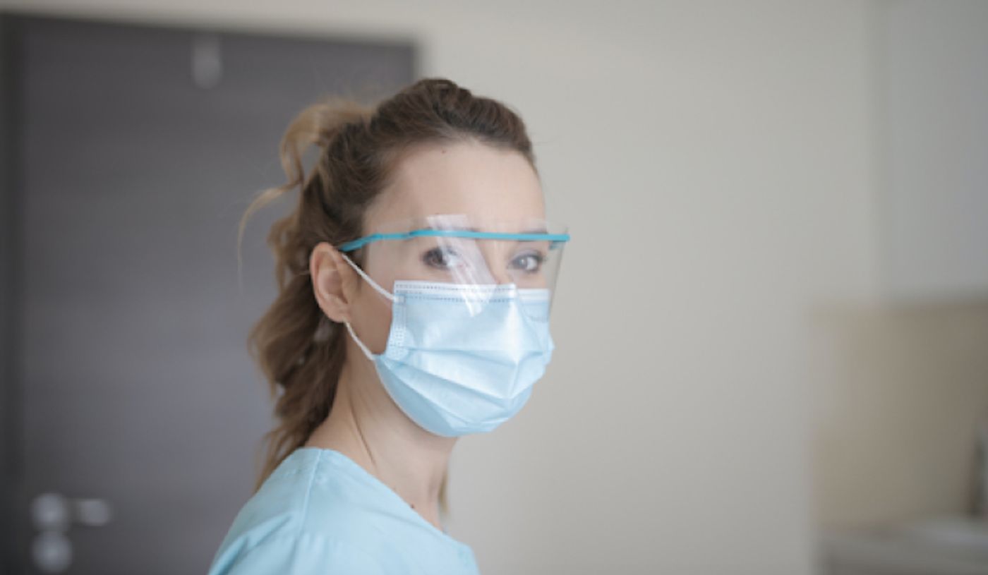 A healthcare worker wearing a mask and face shield