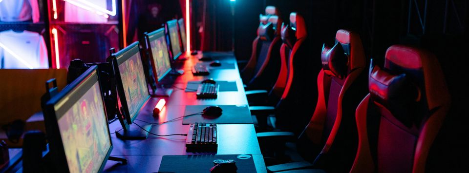 Row of gaming chairs and monitors in a darkened esports setup
