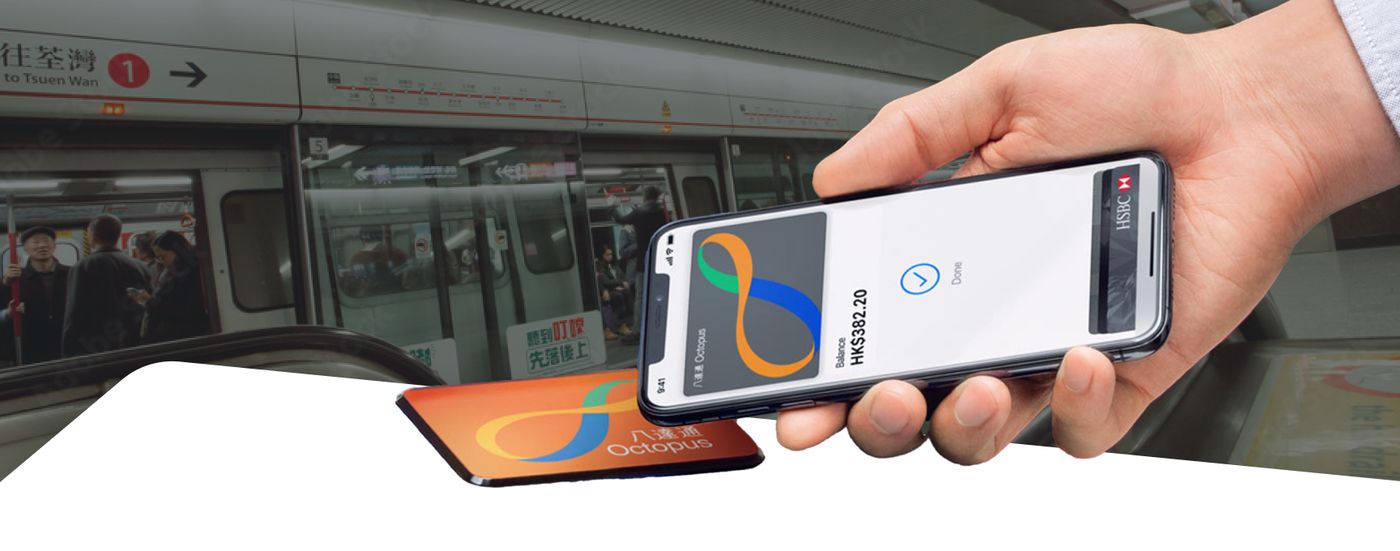 Hand tapping an Octopus card payment on a phone near a Hong Kong subway train