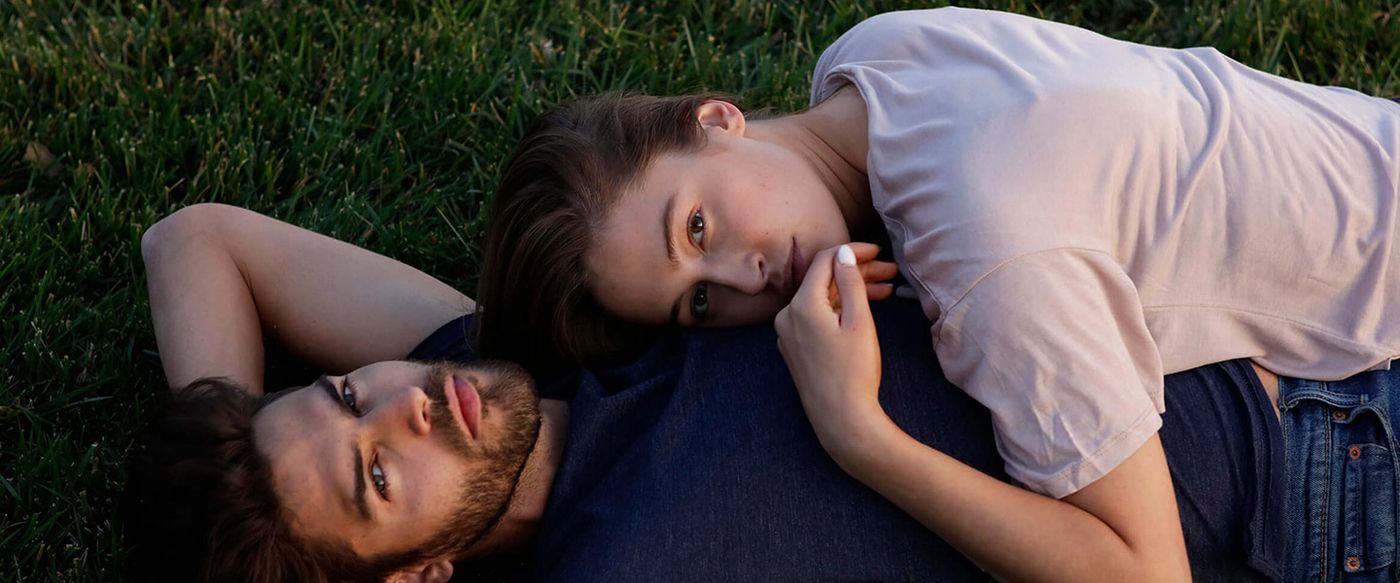 Couple in casual apparel relaxing together on the grass