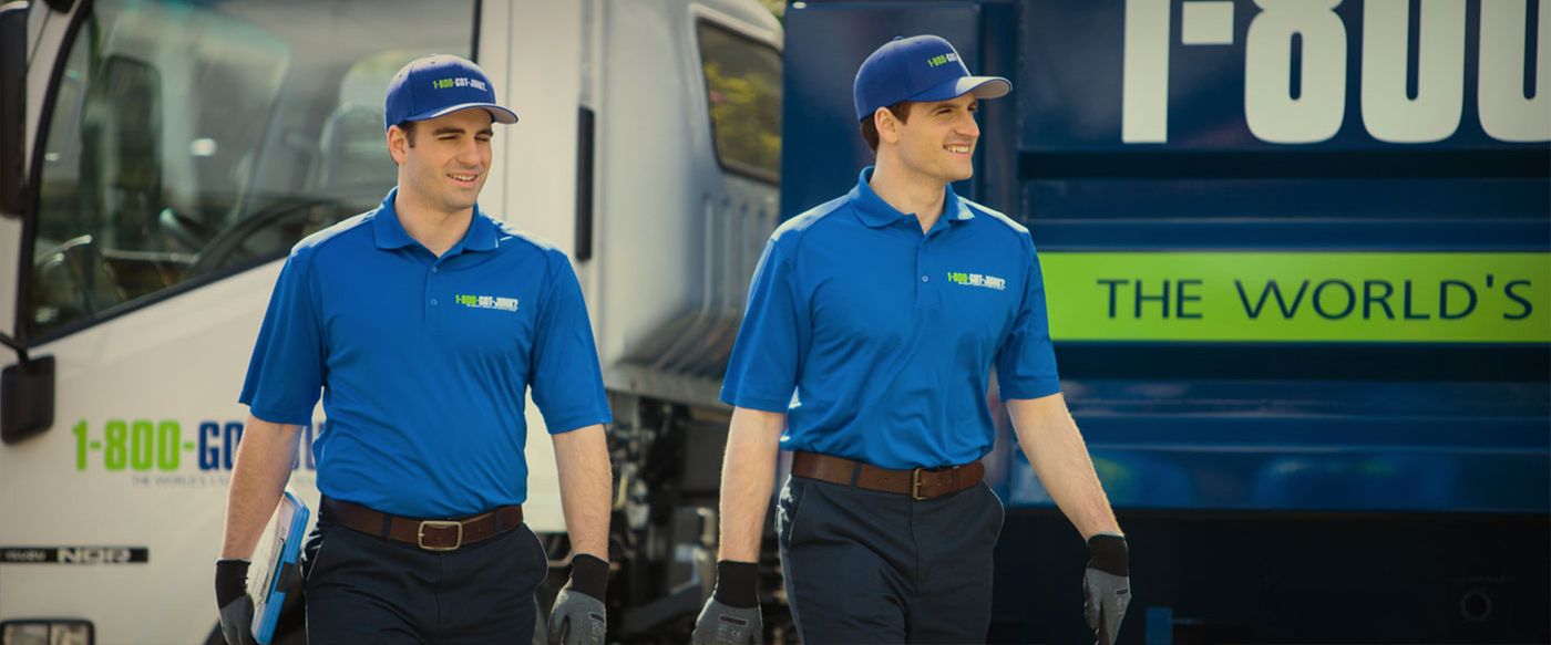 Two 1-800-GOT-JUNK crew members walking past their branded trucks