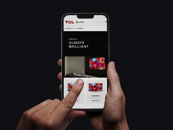 Hand holding a phone on the TCL website showing the B-Series 'Always Brilliant' page