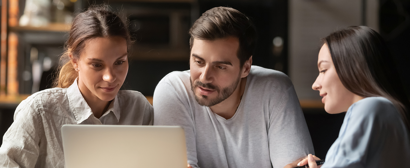 Three colleagues reviewing something together on a laptop
