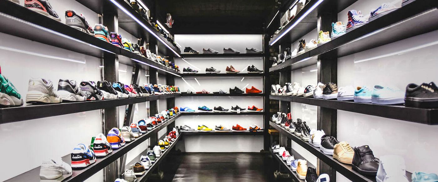 Rows of sneakers displayed on lit shelves in a shoe store