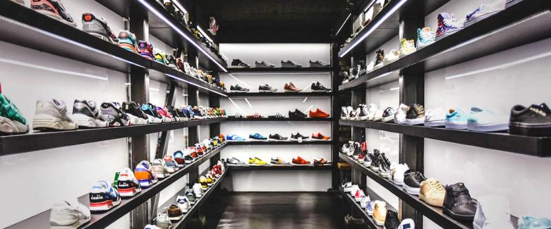 Rows of sneakers displayed on lit shelves in a shoe store