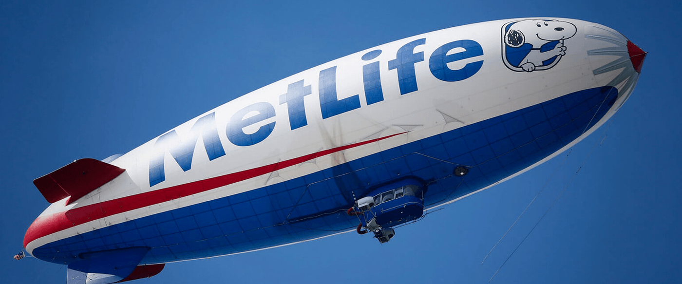 The MetLife blimp featuring Snoopy flies against a clear blue sky