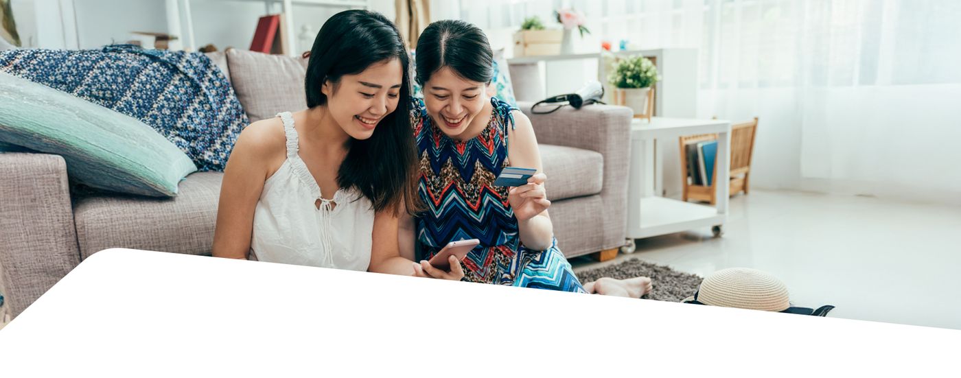 Two women looking at a phone together on a living room sofa