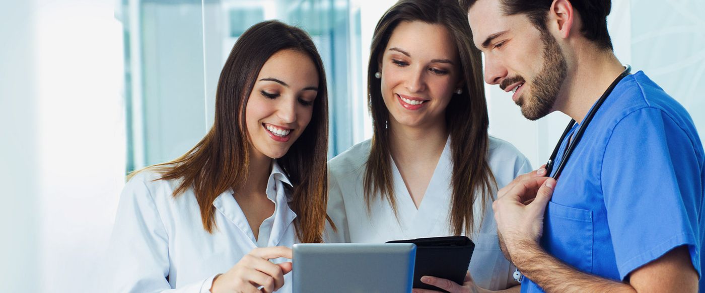 Two colleagues and a clinician reviewing information together on tablets