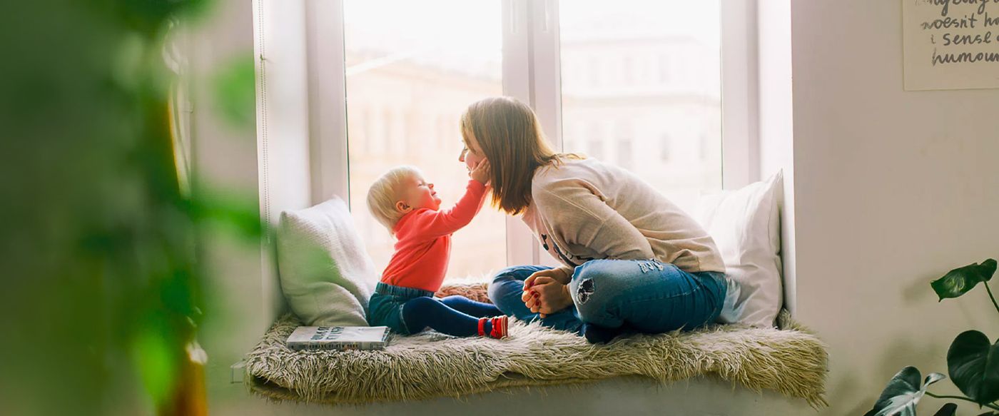Mother and toddler playing together on a window seat at home