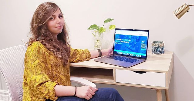 Shazmah Nawaz sitting at a desk at home beside an open laptop