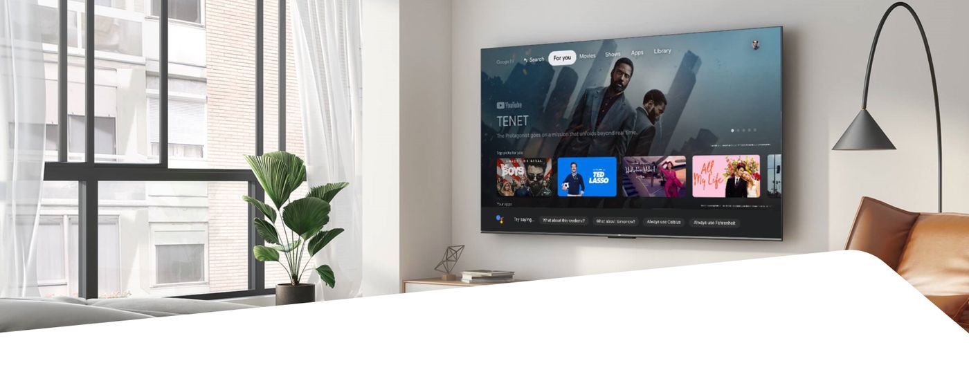 A wall-mounted TCL smart TV showing a streaming home screen in a modern living room