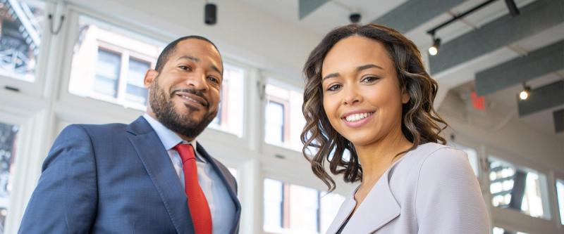 Two smiling accounting professionals posing together in an office