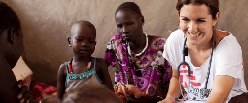 A Doctors Without Borders medical worker examines a child alongside her mother
