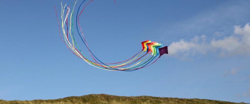 Colorful ribboned kite looping through a clear blue sky