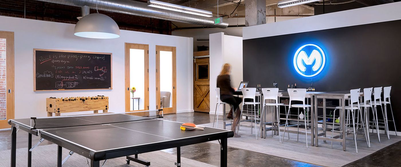 MuleSoft office lounge with a ping pong table, foosball table and glowing M logo on the wall