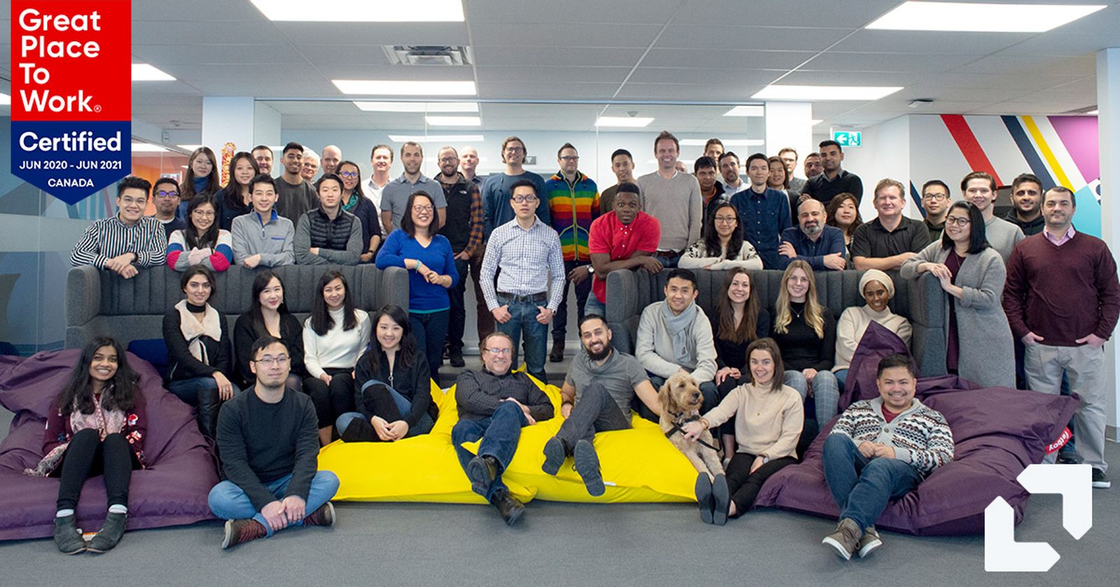 Large Appnovation team posing in the office alongside a Great Place to Work Canada certification badge