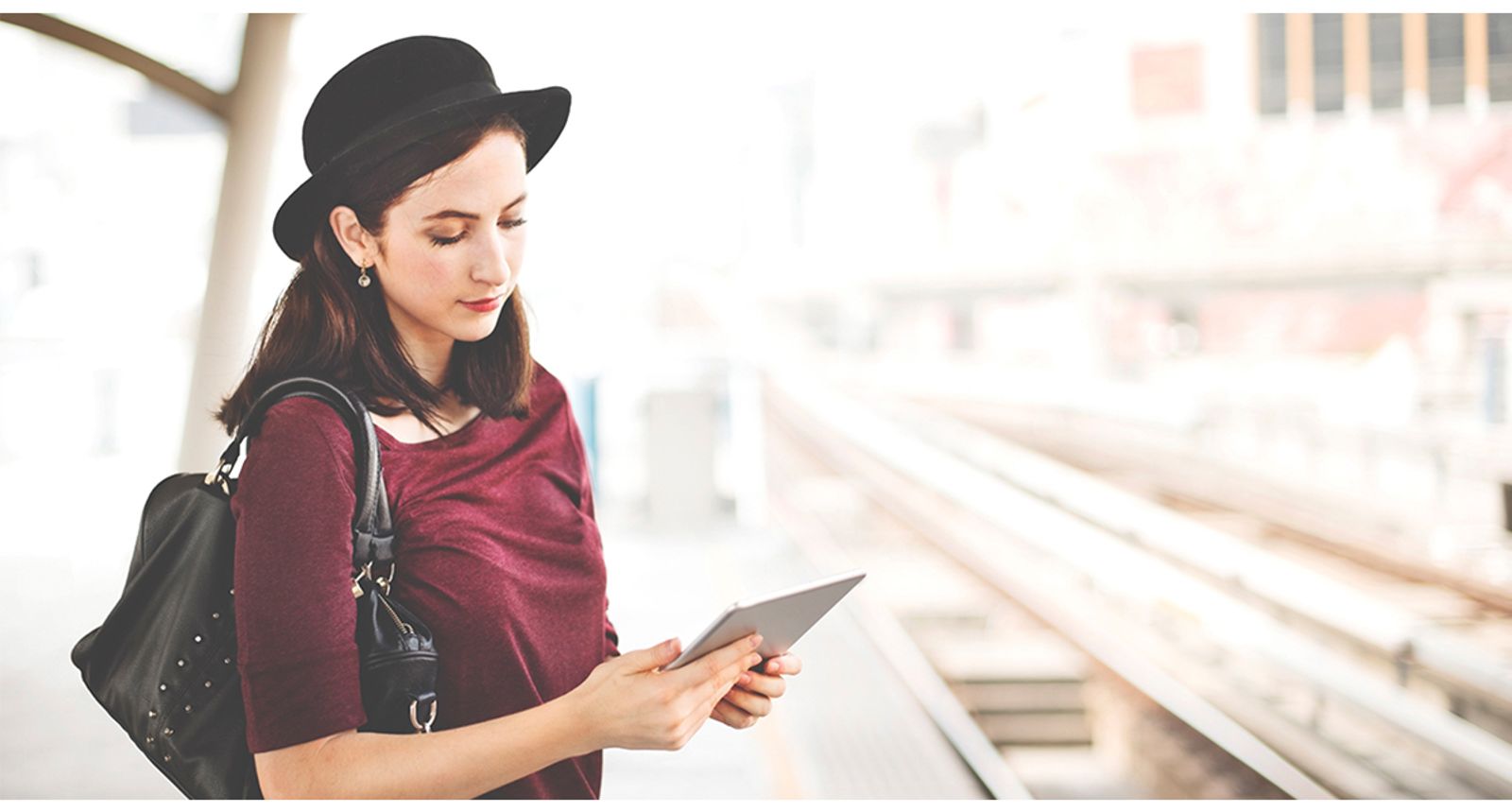 Traveler checking a tablet while waiting at a train platform