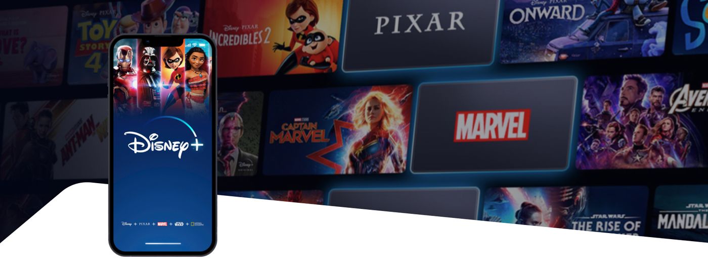 The Disney+ app on a phone screen in front of a grid of Marvel and Pixar titles