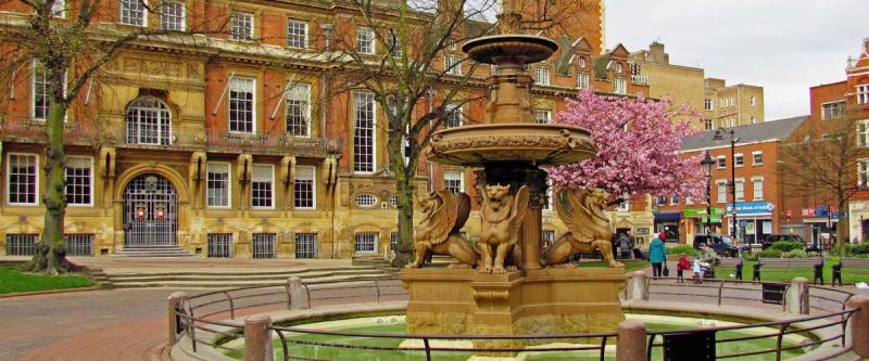 A historic town square with an ornate fountain, lions and a stately building