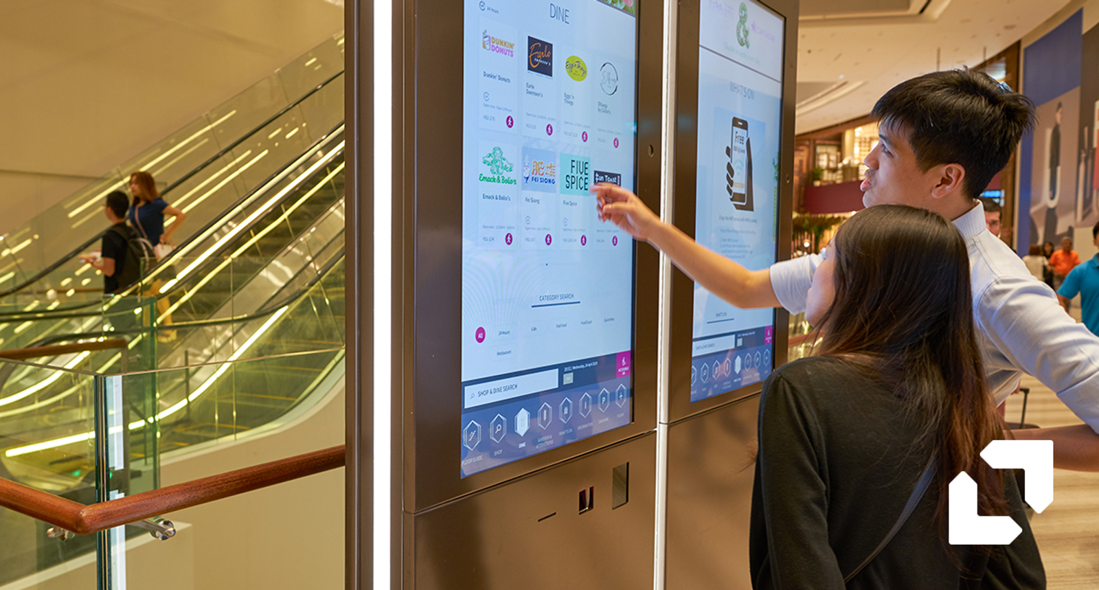 Shoppers using an interactive digital directory screen in a mall