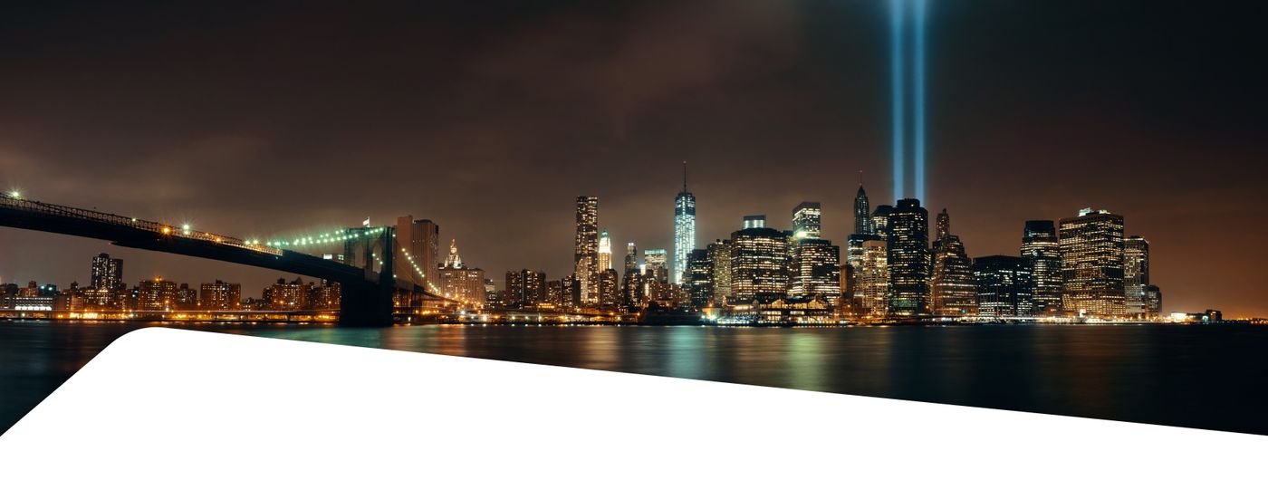 New York City skyline at night with the 9/11 Tribute in Light memorial beams and the Brooklyn Bridge