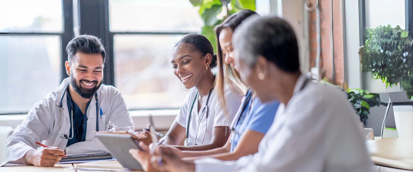 Group of healthcare staff smiling and reviewing notes together in a meeting