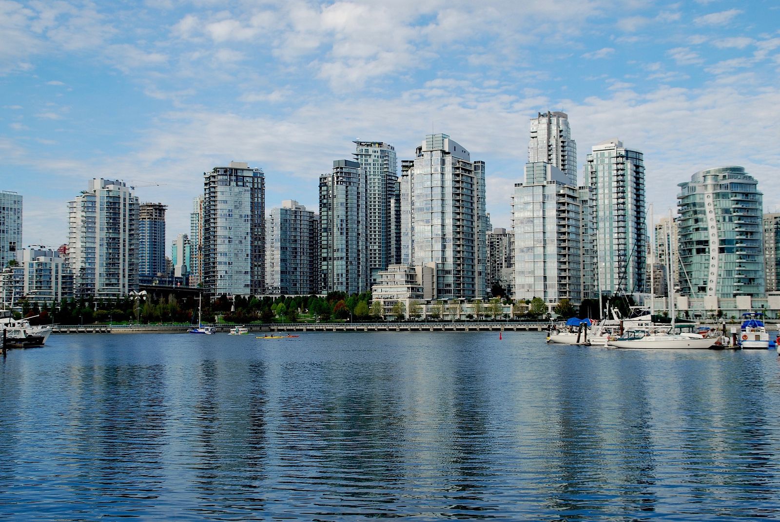 Vancouver's waterfront skyline with condo towers and moored sailboats under a clear sky