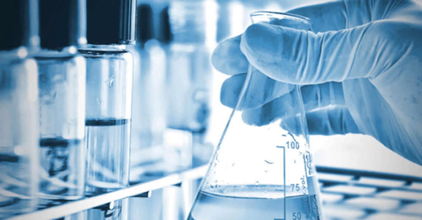 Gloved hand holding a lab flask beside test tubes in a research laboratory