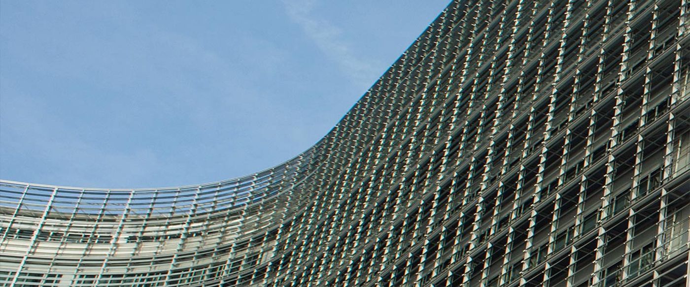 Low-angle view of the curved glass facade of the European Commission's Berlaymont building