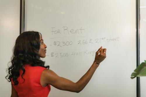 A woman writing real estate facts on a board