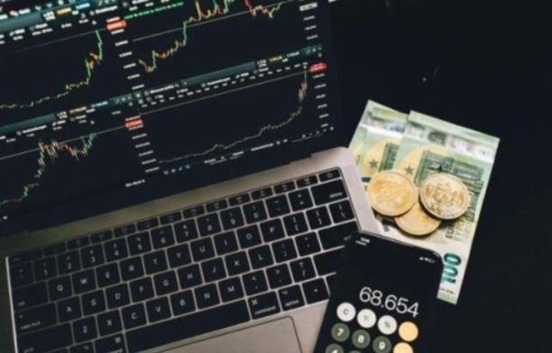 Coins, 100 Notes, A calculator phone app, and a laptop showing the stock market