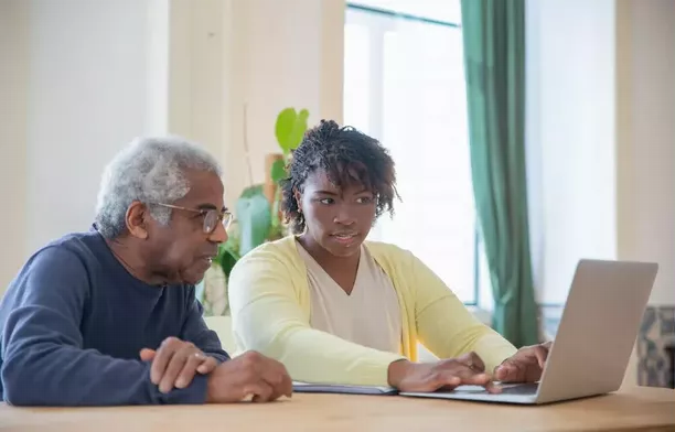 An elderly man and a young woman staring hard into a laptop screen