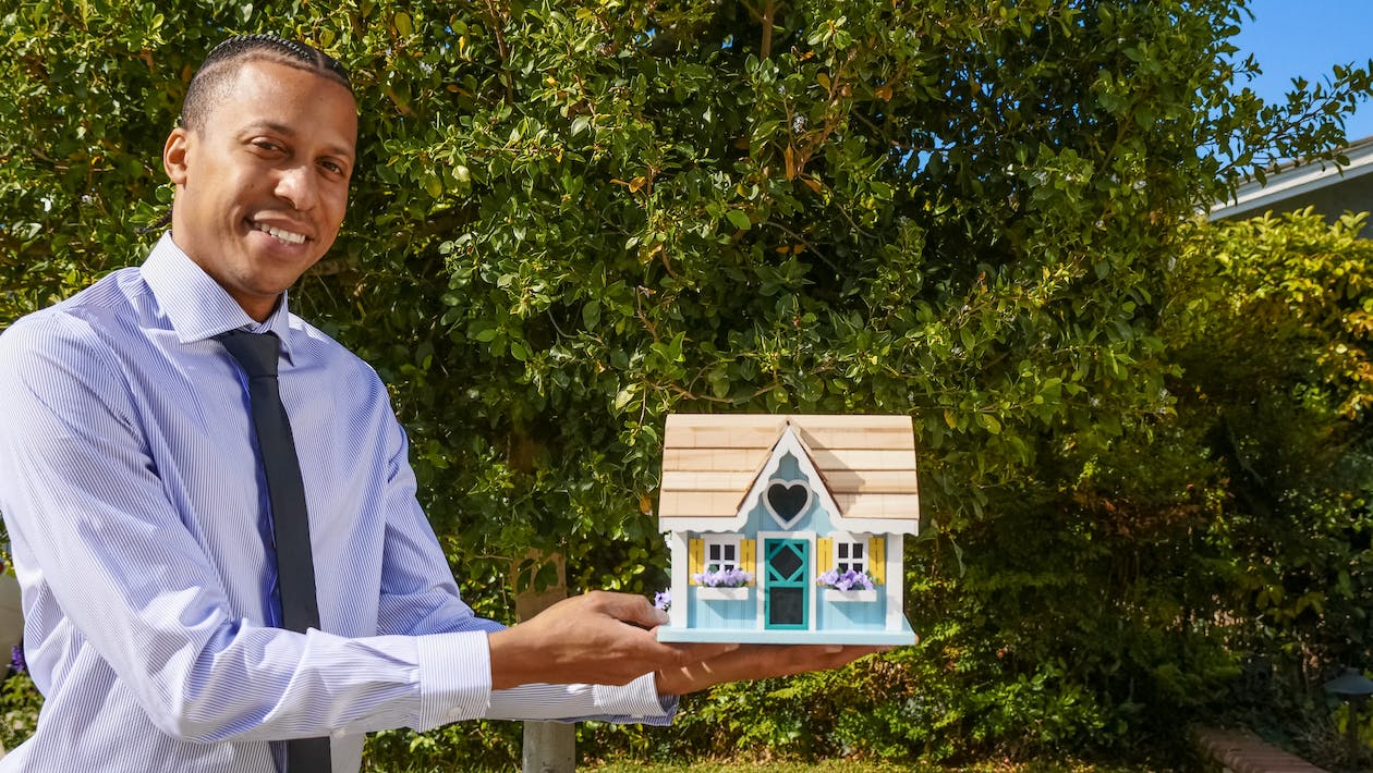 A man holding a model (miniature) wooden house