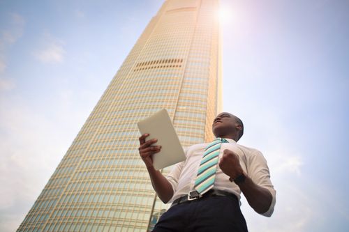 a successful professional man standing in front of a high rise building