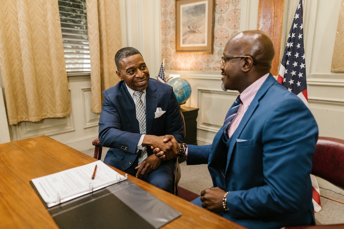 two black men shaking hands in excitement of a sealed agreement