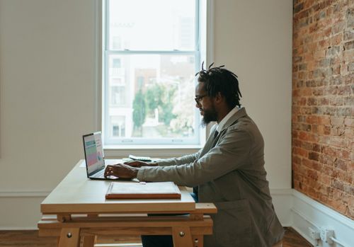 a man sitting on a desk working on his laptop