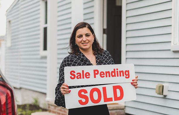 property seller carrying a sale-pending board